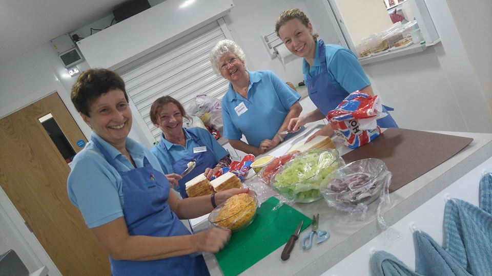 A group of women in blue are preparing food for a cafe