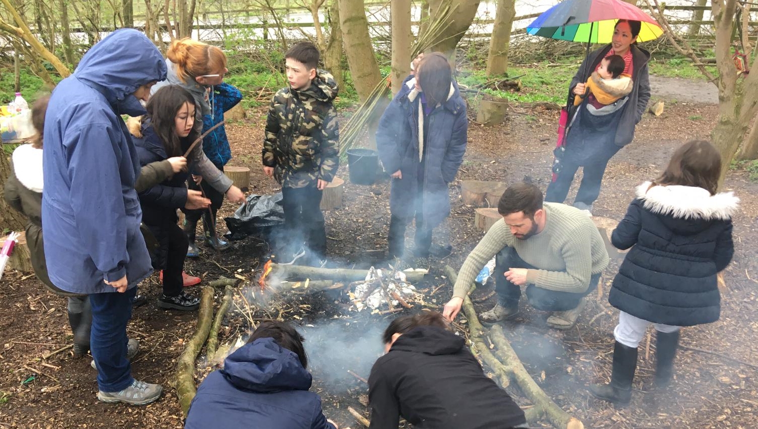 Children and adults gather around a camp fire